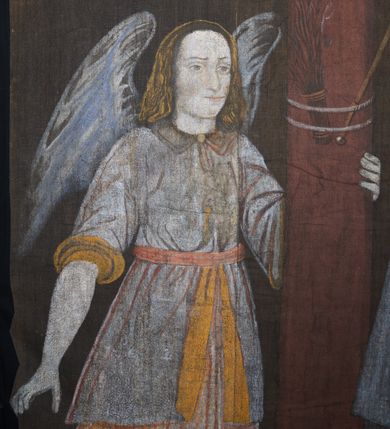 Zdjęcie nr 6: Tkanina wielkopostna przedstawiająca Piętę ukazaną na zszytych fragmentach płótna (25 brytów). W centrum kompozycji stoi krzyż, pod którym siedzi Matka Boska trzymająca na kolanach martwe ciało Chrystusa. Maria zwrócona jest trzy czwarte w lewo,  lewą ręką podtrzymuje rękę syna, prawą obejmuje go w talii, głowę ma przechyloną w lewo. Twarz podłużna o wyraźnych, konturowych rysach, oczy niemal zamknięte, długi nos, wąskie usta. Ubrana jest w jasną suknię o fałdach podkreślonych wyraźnymi konturami, niebieski płaszcz, okrywający nogi, podwikę oraz szary welon na głowie. Wokół głowy ma kolisty, złoty i promienisty nimb. Ciało Chrystusa spoczywa na kolanach Marii. Twarz owalna o konturowych rysach z zamkniętymi oczami, okolona jasnym zarostem, włosy długie z przedziałkiem na środku głowy, opadające na plecy. Ciało blade, ociekające krwią, niemodelowane, podkreślone konturem. Przez biodra przewiązane granatowe perizonium. O ramiona krzyża oparte ukośnie: po lewej włócznia, po prawej gąbka z octem na długim drzewcu. U góry krzyża zawieszony biały titulus w formie banderoli z tytułem winy w trzech językach „INRI”. Po bokach kompozycji u dołu, dwa anioły ukazane w pozycji klęczącej, zwrócone trzy czwarte ku środkowi obrazu. Anioł po prawej stronie trzyma w prawej dłoni drabinę, na której koniec założona jest korona cierniowa, nieco niżej ukazano trzy gwoździe, a wyżej rękawicę żołnierza. Anioł po lewej obejmuje kolumnę biczowania, na której stoi piejący kogut. W górnej części kolumny przywiązane są bicze. Ponad aniołami unoszą się na obłokach dwie kolejne postacie aniołów. Anioły ubrane są w różowe suknie i niebieskie tuniki z żółtą podszewką, przewiązane w pasie złotą taśmą. W górnych narożach obrazu symbole lunarne o ludzkich twarzach: po lewej księżyc, po prawej słońce. Na dole obrazu, pośrodku malowana na czerwono sygnatura „AB”. Po lewej stronie obrazu na wysokości ręki anioła unoszącego się na obłoku fragment daty „16”. Po bokach krzyża kilkuwersowe napisy, słabo czytelne. Według literatury nad głową Matki Boskiej znajduje się napis: „Filia populi ei acingere cilicio recospergere cinere: iuctu Unigenliafe tibi planctu emaru”.  Obok słońca i księżyca kolejny napis: „Ecce videntes clamabunt foris angeli pacis amare flebunt”, a także „amare flebunt angeli pacis”. Kolorystyka blada, w odcieniach zimnych, formy wydobyte konturem.