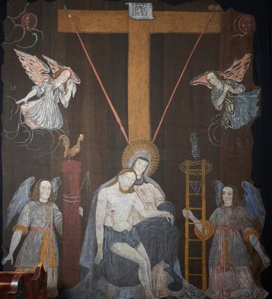 Zdjęcie nr 8: Tkanina wielkopostna przedstawiająca Piętę ukazaną na zszytych fragmentach płótna (25 brytów). W centrum kompozycji stoi krzyż, pod którym siedzi Matka Boska trzymająca na kolanach martwe ciało Chrystusa. Maria zwrócona jest trzy czwarte w lewo,  lewą ręką podtrzymuje rękę syna, prawą obejmuje go w talii, głowę ma przechyloną w lewo. Twarz podłużna o wyraźnych, konturowych rysach, oczy niemal zamknięte, długi nos, wąskie usta. Ubrana jest w jasną suknię o fałdach podkreślonych wyraźnymi konturami, niebieski płaszcz, okrywający nogi, podwikę oraz szary welon na głowie. Wokół głowy ma kolisty, złoty i promienisty nimb. Ciało Chrystusa spoczywa na kolanach Marii. Twarz owalna o konturowych rysach z zamkniętymi oczami, okolona jasnym zarostem, włosy długie z przedziałkiem na środku głowy, opadające na plecy. Ciało blade, ociekające krwią, niemodelowane, podkreślone konturem. Przez biodra przewiązane granatowe perizonium. O ramiona krzyża oparte ukośnie: po lewej włócznia, po prawej gąbka z octem na długim drzewcu. U góry krzyża zawieszony biały titulus w formie banderoli z tytułem winy w trzech językach „INRI”. Po bokach kompozycji u dołu, dwa anioły ukazane w pozycji klęczącej, zwrócone trzy czwarte ku środkowi obrazu. Anioł po prawej stronie trzyma w prawej dłoni drabinę, na której koniec założona jest korona cierniowa, nieco niżej ukazano trzy gwoździe, a wyżej rękawicę żołnierza. Anioł po lewej obejmuje kolumnę biczowania, na której stoi piejący kogut. W górnej części kolumny przywiązane są bicze. Ponad aniołami unoszą się na obłokach dwie kolejne postacie aniołów. Anioły ubrane są w różowe suknie i niebieskie tuniki z żółtą podszewką, przewiązane w pasie złotą taśmą. W górnych narożach obrazu symbole lunarne o ludzkich twarzach: po lewej księżyc, po prawej słońce. Na dole obrazu, pośrodku malowana na czerwono sygnatura „AB”. Po lewej stronie obrazu na wysokości ręki anioła unoszącego się na obłoku fragment daty „16”. Po bokach krzyża kilkuwersowe napisy, słabo czytelne. Według literatury nad głową Matki Boskiej znajduje się napis: „Filia populi ei acingere cilicio recospergere cinere: iuctu Unigenliafe tibi planctu emaru”.  Obok słońca i księżyca kolejny napis: „Ecce videntes clamabunt foris angeli pacis amare flebunt”, a także „amare flebunt angeli pacis”. Kolorystyka blada, w odcieniach zimnych, formy wydobyte konturem.