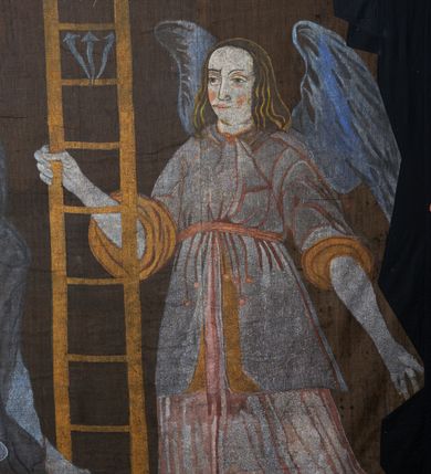 Zdjęcie nr 10: Tkanina wielkopostna przedstawiająca Piętę ukazaną na zszytych fragmentach płótna (25 brytów). W centrum kompozycji stoi krzyż, pod którym siedzi Matka Boska trzymająca na kolanach martwe ciało Chrystusa. Maria zwrócona jest trzy czwarte w lewo,  lewą ręką podtrzymuje rękę syna, prawą obejmuje go w talii, głowę ma przechyloną w lewo. Twarz podłużna o wyraźnych, konturowych rysach, oczy niemal zamknięte, długi nos, wąskie usta. Ubrana jest w jasną suknię o fałdach podkreślonych wyraźnymi konturami, niebieski płaszcz, okrywający nogi, podwikę oraz szary welon na głowie. Wokół głowy ma kolisty, złoty i promienisty nimb. Ciało Chrystusa spoczywa na kolanach Marii. Twarz owalna o konturowych rysach z zamkniętymi oczami, okolona jasnym zarostem, włosy długie z przedziałkiem na środku głowy, opadające na plecy. Ciało blade, ociekające krwią, niemodelowane, podkreślone konturem. Przez biodra przewiązane granatowe perizonium. O ramiona krzyża oparte ukośnie: po lewej włócznia, po prawej gąbka z octem na długim drzewcu. U góry krzyża zawieszony biały titulus w formie banderoli z tytułem winy w trzech językach „INRI”. Po bokach kompozycji u dołu, dwa anioły ukazane w pozycji klęczącej, zwrócone trzy czwarte ku środkowi obrazu. Anioł po prawej stronie trzyma w prawej dłoni drabinę, na której koniec założona jest korona cierniowa, nieco niżej ukazano trzy gwoździe, a wyżej rękawicę żołnierza. Anioł po lewej obejmuje kolumnę biczowania, na której stoi piejący kogut. W górnej części kolumny przywiązane są bicze. Ponad aniołami unoszą się na obłokach dwie kolejne postacie aniołów. Anioły ubrane są w różowe suknie i niebieskie tuniki z żółtą podszewką, przewiązane w pasie złotą taśmą. W górnych narożach obrazu symbole lunarne o ludzkich twarzach: po lewej księżyc, po prawej słońce. Na dole obrazu, pośrodku malowana na czerwono sygnatura „AB”. Po lewej stronie obrazu na wysokości ręki anioła unoszącego się na obłoku fragment daty „16”. Po bokach krzyża kilkuwersowe napisy, słabo czytelne. Według literatury nad głową Matki Boskiej znajduje się napis: „Filia populi ei acingere cilicio recospergere cinere: iuctu Unigenliafe tibi planctu emaru”.  Obok słońca i księżyca kolejny napis: „Ecce videntes clamabunt foris angeli pacis amare flebunt”, a także „amare flebunt angeli pacis”. Kolorystyka blada, w odcieniach zimnych, formy wydobyte konturem.