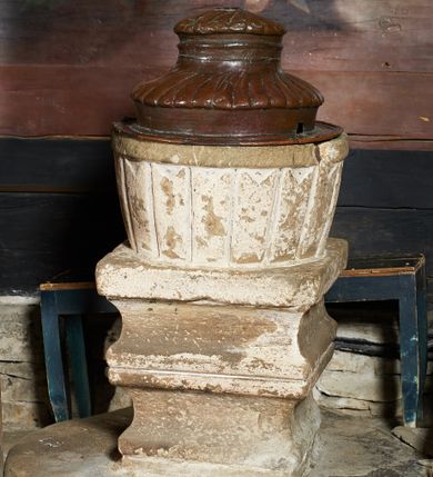 Zdjęcie nr 1: Chrzcielnica ustawiona na wysokiej stopie na na planie koła. Trzon w formie dwóch kostek o wklęsłych bokach, oddzielonych kwadratowym pierścieniem od czary. Czara na planie koła, delikatnie rozszerzająca się ku górze, dekorowana rytymi pionowymi pasami, zakończona profilowanym wylewem. Pokrywa miedziana, na planie koła z kryzą, dwustopniowa, na każdym stopniu dekorowana puklowanym nakryciem. Chrzcielnica pobielona.