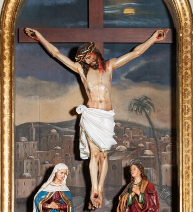 Zdjęcie nr 6: Ołtarz przyścienny, architektoniczny, jednoosiowy, jednokondygnacyjny. Mensa skrzyniowa, prostopadłościenna, z kamiennym portatylem, ustawiona na niskiej podstawie, antepedium ujęte płaskimi listwami łączącymi się z owalnym polem, pośrodku którego jest aplikowany, pozłacany krzyż. Predella wysoka, ujęta po bokach konsolami w formie uproszczonych wolut z nieznacznie wysuniętym architektonicznym tabernakulum, ujętym kanelowanymi pilastrami, podtrzymującymi belkowanie i trójkątny przyczółek. Pomiędzy pilastrami drzwiczki prostokątne, w których płycina w formie prostokąta o wklęsłych ćwierćkoliście narożach z malowanym ornamentem akantowym i kielichem z hostią pośrodku. Po bokach tabernakulum dwie marmoryzowane płyciny w kształcie kwadratu z uszakami. Nastawa ołtarzowa flankowana dwiema kolumnami jońskimi wspierającymi belkowanie z silnie wysuniętym gzymsem. Pole środkowe w formie głębokiej, prostokątnej, zamkniętej półkoliście wnęki o dekoracyjnej ramie, wewnątrz której umieszczona jest rzeźbiona grupa Ukrzyżowania na tle malowanego widoku Jerozolimy. Pola pomiędzy wnęką a kolumnami wypełnione są stylizowaną, profilowaną arkadą z archiwoltą wspartą na toskańskich kapitelach, pod którymi podwieszone są łezki. W górnej części arkady, po bokach znajdują się dwie płyciny wypełnione malowaną, białą  dekoracją roślinną na brązowym tle, a pomiędzy nimi jest w owalu rzeźbiona i złocona rozeta. Całość struktury ołtarza polichromowana i marmoryzowana jest w odcieniach beżu i szarości.