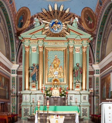 Zdjęcie nr 1: Nastawa architektoniczna, trójosiowa, jednokondygnacyjna ze zwieńczeniem, na podwójnym cokole zakończonym gzymsem. Ołtarz i mensa w marmurowej okładzinie, ustawione na czterostopniowym podwyższeniu na planie prostokąta o ściętych narożach. Tabernakulum w kształcie prostopadłościennej skrzynki, ujęte czterema kolumnami w narożach. Drzwiczki dwuskrzydłowe z aplikowanymi kielichem z hostią w glorii w otoczeniu kłosów zbóż i winnego grona. Tron wystawienia w formie półkolistej glorietty oraz półkopuły, zwieńczonej kulą z krzyżem.Osie wydzielone są dwiema parami kolumn korynckich, dźwigających pełne belkowanie wyłamane w ich partii oraz przerwany przyczółek z klęczącą parą aniołów. W polu osi bocznych pilastry; na ich tle wsporniki z figurami św. Piotra po lewej i św. Pawła po prawej. W polu środkowym rama w formie stojącego prostokąta, we wnęce płaskorzeźbione przedstawienie Matki Boskiej Różańcowej. Zwieńczenie w kształcie promienistej glorii o naprzemiennych falistych i prostych wiązkach promieni z rzeźbioną półpostacią Boga Ojca pośród obłoków. Cokoły dekorowane płycinami w formie stojącego prostokąta z uszakami. Rama obrazu profilowana, zdobiona kimationem; na wewnętrznych ściankach wnęki bujny akant. U spodu obrazu dwie wiązki akantu. Wsporniki dla figur utworzone są z palmet akantu oraz tralek. Architraw dekorowany jajownikiem oraz pasem perełkowania; fryz zdobiony stylizowanym akantem, nad polem środkowym ornament roślinny, na osiach kolumn rozety. Gzyms belkowania i przyczółka dekorowany kimationem, kostkowaniem i perełkowaniem.
Nastawa polichromowana na kolor jasnozielony z ciemnozielonymi detalami; kolumny, ornamentyka oraz detale architektoniczne złocone.