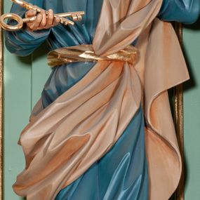 Zdjęcie nr 1: Rzeźba pełna, przedstawiająca św. Piotra. Święty ustawiony frontalnie z głową skierowaną w górę, przechyloną delikatnie w lewą stronę. W prawej, wyciągniętej przed siebie dłoni trzyma dwa złote klucze, a lewą unosi w geście oratorskim. Twarz szeroka, o delikatnie rzeźbionych rysach, oczach skierowanych ku górze; okolona krótką brodą. Włosy średniej długości, brązowe, delikatnie falowane, zasłaniające uszy. Ubrany jest w niebieską suknię, sięgającą do kostek ze złotą lamówką u szyi, przewiązaną w talii szerokim, złotym pasem. Przez lewe ramię i biodro przerzucony jest diagonalnie beżowy płaszcz. Spod tuniki widoczne są na stopach złote sandały.
Polichromia w odsłoniętych partiach ciała naturalistyczna, detale złocone.