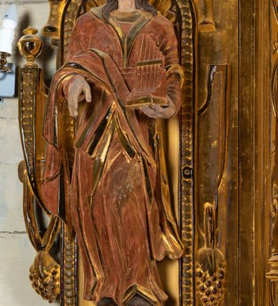 Zdjęcie nr 9: Ołtarz przyścienny, dwukondygnacyjny, jednoosiowy o formach architektonicznych; uszaty. Mensa drewniana, prostopadłościenna; antependium ujęte płaskorzeźbioną, złoconą ramą z dekoracją akantową. Lico malowane z monogramem maryjnym w otoczeniu barwnej dekoracji roślinno-kwiatowej na jasnobeżowym tle. W predelli rama w kształcie leżącego prostokąta ujęta ornamentem kartuszowym mieszcząca pierwotnie niezachowaną dekorację malarską. Nastawa ustawiona na wysokim cokole, ujęta kompozytowymi kolumnami dźwigającymi przełamujące się na osiach podpór pełne belkowanie z kostkowanym achitrawem, płaskorzeźbionym w motyw akantu i uskrzydlonych główek anielskich fryzem oraz wydatnym gzymsem. Kolumny w jednej trzeciej wysokości ujęte profilowanymi opaskami; trzony poniżej opasek zdobione motywem główek anielskich; powyżej płaskorzeźbiona dekoracja arabeskowa. W polu ołtarza prostokątna rama zamknięta łukiem półokrągłym mieszcząca obraz św. Mikołaja; w przyłuczach ramy umieszczone płaskorzeźbione, uskrzydlone główki anielskie. Kondygnacja druga ujęta hermowymi pilastrami dźwigającymi uproszczone belkowanie z wydatnym gzymsem. W polu obraz św. Benedykta o kształcie stojącego prostokąta w złoconej, profilowanej ramie. Na osiach kolumn, ustawione rzeźby św. Piotra (z prawej) i św. Pawła (z lewej) na tle esowatych wolut. Całość nastawy ujęta ażurowymi uszami utworzonymi z ornamentu okuciowego mieszczącymi nisze z rzeźbami św. Cecylii (z lewej) oraz św. Teresy z Avila (z prawej) umieszczonymi na tle muszli. Ponad niszami maszkarony trzymające w pyskach spływające do dołu draperie. Struktura ołtarza oraz partie szat postaci złocone; karnacje rzeźb polichromowane.
