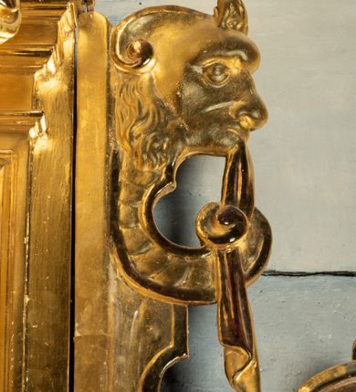 Zdjęcie nr 23: Ołtarz przyścienny, dwukondygnacyjny, jednoosiowy o formach architektonicznych; uszaty. Mensa drewniana, prostopadłościenna; antependium ujęte płaskorzeźbioną, złoconą ramą z dekoracją akantową. Lico malowane z monogramem maryjnym w otoczeniu barwnej dekoracji roślinno-kwiatowej na jasnobeżowym tle. W predelli rama w kształcie leżącego prostokąta ujęta ornamentem kartuszowym mieszcząca pierwotnie niezachowaną dekorację malarską. Nastawa ustawiona na wysokim cokole, ujęta kompozytowymi kolumnami dźwigającymi przełamujące się na osiach podpór pełne belkowanie z kostkowanym achitrawem, płaskorzeźbionym w motyw akantu i uskrzydlonych główek anielskich fryzem oraz wydatnym gzymsem. Kolumny w jednej trzeciej wysokości ujęte profilowanymi opaskami; trzony poniżej opasek zdobione motywem główek anielskich; powyżej płaskorzeźbiona dekoracja arabeskowa. W polu ołtarza prostokątna rama zamknięta łukiem półokrągłym mieszcząca obraz św. Mikołaja; w przyłuczach ramy umieszczone płaskorzeźbione, uskrzydlone główki anielskie. Kondygnacja druga ujęta hermowymi pilastrami dźwigającymi uproszczone belkowanie z wydatnym gzymsem. W polu obraz św. Benedykta o kształcie stojącego prostokąta w złoconej, profilowanej ramie. Na osiach kolumn, ustawione rzeźby św. Piotra (z prawej) i św. Pawła (z lewej) na tle esowatych wolut. Całość nastawy ujęta ażurowymi uszami utworzonymi z ornamentu okuciowego mieszczącymi nisze z rzeźbami św. Cecylii (z lewej) oraz św. Teresy z Avila (z prawej) umieszczonymi na tle muszli. Ponad niszami maszkarony trzymające w pyskach spływające do dołu draperie. Struktura ołtarza oraz partie szat postaci złocone; karnacje rzeźb polichromowane.
