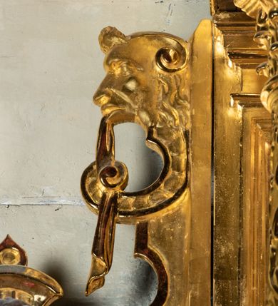 Zdjęcie nr 21: Ołtarz przyścienny, dwukondygnacyjny, jednoosiowy o formach architektonicznych; uszaty. Mensa drewniana, prostopadłościenna; antependium ujęte płaskorzeźbioną, złoconą ramą z dekoracją akantową. Lico malowane z monogramem maryjnym w otoczeniu barwnej dekoracji roślinno-kwiatowej na jasnobeżowym tle. W predelli rama w kształcie leżącego prostokąta ujęta ornamentem kartuszowym mieszcząca pierwotnie niezachowaną dekorację malarską. Nastawa ustawiona na wysokim cokole, ujęta kompozytowymi kolumnami dźwigającymi przełamujące się na osiach podpór pełne belkowanie z kostkowanym achitrawem, płaskorzeźbionym w motyw akantu i uskrzydlonych główek anielskich fryzem oraz wydatnym gzymsem. Kolumny w jednej trzeciej wysokości ujęte profilowanymi opaskami; trzony poniżej opasek zdobione motywem główek anielskich; powyżej płaskorzeźbiona dekoracja arabeskowa. W polu ołtarza prostokątna rama zamknięta łukiem półokrągłym mieszcząca obraz św. Mikołaja; w przyłuczach ramy umieszczone płaskorzeźbione, uskrzydlone główki anielskie. Kondygnacja druga ujęta hermowymi pilastrami dźwigającymi uproszczone belkowanie z wydatnym gzymsem. W polu obraz św. Benedykta o kształcie stojącego prostokąta w złoconej, profilowanej ramie. Na osiach kolumn, ustawione rzeźby św. Piotra (z prawej) i św. Pawła (z lewej) na tle esowatych wolut. Całość nastawy ujęta ażurowymi uszami utworzonymi z ornamentu okuciowego mieszczącymi nisze z rzeźbami św. Cecylii (z lewej) oraz św. Teresy z Avila (z prawej) umieszczonymi na tle muszli. Ponad niszami maszkarony trzymające w pyskach spływające do dołu draperie. Struktura ołtarza oraz partie szat postaci złocone; karnacje rzeźb polichromowane.
