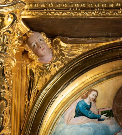 Zdjęcie nr 24: Ołtarz przyścienny, dwukondygnacyjny, jednoosiowy o formach architektonicznych; uszaty. Mensa drewniana, prostopadłościenna; antependium ujęte płaskorzeźbioną, złoconą ramą z dekoracją akantową. Lico malowane z monogramem maryjnym w otoczeniu barwnej dekoracji roślinno-kwiatowej na jasnobeżowym tle. W predelli rama w kształcie leżącego prostokąta ujęta ornamentem kartuszowym mieszcząca pierwotnie niezachowaną dekorację malarską. Nastawa ustawiona na wysokim cokole, ujęta kompozytowymi kolumnami dźwigającymi przełamujące się na osiach podpór pełne belkowanie z kostkowanym achitrawem, płaskorzeźbionym w motyw akantu i uskrzydlonych główek anielskich fryzem oraz wydatnym gzymsem. Kolumny w jednej trzeciej wysokości ujęte profilowanymi opaskami; trzony poniżej opasek zdobione motywem główek anielskich; powyżej płaskorzeźbiona dekoracja arabeskowa. W polu ołtarza prostokątna rama zamknięta łukiem półokrągłym mieszcząca obraz św. Mikołaja; w przyłuczach ramy umieszczone płaskorzeźbione, uskrzydlone główki anielskie. Kondygnacja druga ujęta hermowymi pilastrami dźwigającymi uproszczone belkowanie z wydatnym gzymsem. W polu obraz św. Benedykta o kształcie stojącego prostokąta w złoconej, profilowanej ramie. Na osiach kolumn, ustawione rzeźby św. Piotra (z prawej) i św. Pawła (z lewej) na tle esowatych wolut. Całość nastawy ujęta ażurowymi uszami utworzonymi z ornamentu okuciowego mieszczącymi nisze z rzeźbami św. Cecylii (z lewej) oraz św. Teresy z Avila (z prawej) umieszczonymi na tle muszli. Ponad niszami maszkarony trzymające w pyskach spływające do dołu draperie. Struktura ołtarza oraz partie szat postaci złocone; karnacje rzeźb polichromowane.
