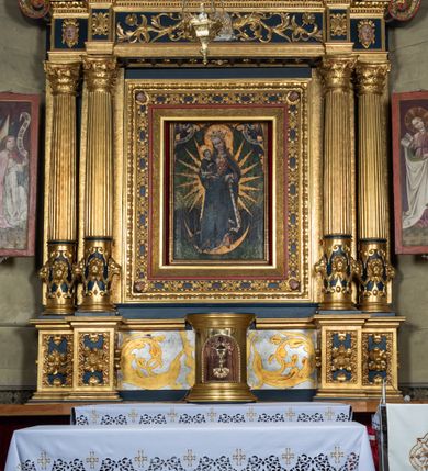 Zdjęcie nr 2: Nastawa ołtarzowa drewniana, architektoniczna, jednoosiowa, jednokondygnacyjna z predellą i zwieńczeniem. Retabulum na wysokim cokole zwieńczonym profilowanym gzymsem; lica wypełnione złoconym ornamentem kwiatowym i winnymi gronami. Predella srebrzona z rytym, złoconym ornamentem akantowym; za tabernakulum, na osi predelli wypukły kartusz z napisem: AVE REGINA COELORUM/ MATER REGIS ANGELORUM. O MARIA/ FLOS VIRGINUM/ VELUT ROSA VEL LILIUM/ FUNDE PRAECES AD FILIUM/ PRO SALUTE FIDELIUM. Nastawa ujęta parą zdwojonych kolumn o kompozytowych kapitelach; trzony w 1/3 wysokości przedzielone pierścieniem, w dolnej partii z dekoracją snycerską (płaskorzeźbione lwie główki, kaboszony, ornament okuciowy); w górnej części kanelowane. Kolumny podtrzymują pełne belkowanie przełamane na osi kolumn, zwieńczone trójkątnym, przerwanym przyczółkiem, na którym półleżące postacie aniołów. Na drugim planie, po bokach przyczółka profilowane, złocone spływy wolutowe. Gzymsy profilowane, złocone z kostkowaniem i kimationem. W zwieńczeniu, na osi ołtarza pełnoplastyczna, polichromowana figura Chrystusa Zmartwychwstałego. W polu środkowym ołtarza prostokątna, rozglifiona płycina w bogatym, płaskorzeźbionym i złoconym obramieniu mieszcząca obraz Matki Boskiej Niepokalanie Poczętej. W narożach obramienia płaskorzeźbione i polichromowane główki anielskie. Na podniebiu architrawu złocone róże umieszczone w prostokątnych kasetonach; w partii fryzu złocony ornament roślinny z umieszczonym na osi monogramem Marii. W polach na osi kolumn ornament kartuszowy z rautami (w osiach środkowych) oraz płaskorzeźbione i polichromowane główki kobiece (w osiach skrajnych). Tabernakulum drewniane o formach architektonicznych, z wypukłym licem, ustawione na mensie, na osi ołtarza na niewysokim, profilowanym i złoconym cokole, zwieńczone analogicznym gzymsem. Na drzwiczkach płaskorzeźbiony kielich z hostią. Struktura ołtarza polichromowana na kolor ciemnozielony z elementami ciemnej czerwieni i złocona; partie ornamentów i załamania profili architektonicznych złocone. 