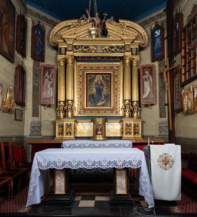 Zdjęcie nr 23: Nastawa ołtarzowa drewniana, architektoniczna, jednoosiowa, jednokondygnacyjna z predellą i zwieńczeniem. Retabulum na wysokim cokole zwieńczonym profilowanym gzymsem; lica wypełnione złoconym ornamentem kwiatowym i winnymi gronami. Predella srebrzona z rytym, złoconym ornamentem akantowym; za tabernakulum, na osi predelli wypukły kartusz z napisem: AVE REGINA COELORUM/ MATER REGIS ANGELORUM. O MARIA/ FLOS VIRGINUM/ VELUT ROSA VEL LILIUM/ FUNDE PRAECES AD FILIUM/ PRO SALUTE FIDELIUM. Nastawa ujęta parą zdwojonych kolumn o kompozytowych kapitelach; trzony w 1/3 wysokości przedzielone pierścieniem, w dolnej partii z dekoracją snycerską (płaskorzeźbione lwie główki, kaboszony, ornament okuciowy); w górnej części kanelowane. Kolumny podtrzymują pełne belkowanie przełamane na osi kolumn, zwieńczone trójkątnym, przerwanym przyczółkiem, na którym półleżące postacie aniołów. Na drugim planie, po bokach przyczółka profilowane, złocone spływy wolutowe. Gzymsy profilowane, złocone z kostkowaniem i kimationem. W zwieńczeniu, na osi ołtarza pełnoplastyczna, polichromowana figura Chrystusa Zmartwychwstałego. W polu środkowym ołtarza prostokątna, rozglifiona płycina w bogatym, płaskorzeźbionym i złoconym obramieniu mieszcząca obraz Matki Boskiej Niepokalanie Poczętej. W narożach obramienia płaskorzeźbione i polichromowane główki anielskie. Na podniebiu architrawu złocone róże umieszczone w prostokątnych kasetonach; w partii fryzu złocony ornament roślinny z umieszczonym na osi monogramem Marii. W polach na osi kolumn ornament kartuszowy z rautami (w osiach środkowych) oraz płaskorzeźbione i polichromowane główki kobiece (w osiach skrajnych). Tabernakulum drewniane o formach architektonicznych, z wypukłym licem, ustawione na mensie, na osi ołtarza na niewysokim, profilowanym i złoconym cokole, zwieńczone analogicznym gzymsem. Na drzwiczkach płaskorzeźbiony kielich z hostią. Struktura ołtarza polichromowana na kolor ciemnozielony z elementami ciemnej czerwieni i złocona; partie ornamentów i załamania profili architektonicznych złocone. 