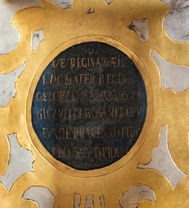 Zdjęcie nr 25: Nastawa ołtarzowa drewniana, architektoniczna, jednoosiowa, jednokondygnacyjna z predellą i zwieńczeniem. Retabulum na wysokim cokole zwieńczonym profilowanym gzymsem; lica wypełnione złoconym ornamentem kwiatowym i winnymi gronami. Predella srebrzona z rytym, złoconym ornamentem akantowym; za tabernakulum, na osi predelli wypukły kartusz z napisem: AVE REGINA COELORUM/ MATER REGIS ANGELORUM. O MARIA/ FLOS VIRGINUM/ VELUT ROSA VEL LILIUM/ FUNDE PRAECES AD FILIUM/ PRO SALUTE FIDELIUM. Nastawa ujęta parą zdwojonych kolumn o kompozytowych kapitelach; trzony w 1/3 wysokości przedzielone pierścieniem, w dolnej partii z dekoracją snycerską (płaskorzeźbione lwie główki, kaboszony, ornament okuciowy); w górnej części kanelowane. Kolumny podtrzymują pełne belkowanie przełamane na osi kolumn, zwieńczone trójkątnym, przerwanym przyczółkiem, na którym półleżące postacie aniołów. Na drugim planie, po bokach przyczółka profilowane, złocone spływy wolutowe. Gzymsy profilowane, złocone z kostkowaniem i kimationem. W zwieńczeniu, na osi ołtarza pełnoplastyczna, polichromowana figura Chrystusa Zmartwychwstałego. W polu środkowym ołtarza prostokątna, rozglifiona płycina w bogatym, płaskorzeźbionym i złoconym obramieniu mieszcząca obraz Matki Boskiej Niepokalanie Poczętej. W narożach obramienia płaskorzeźbione i polichromowane główki anielskie. Na podniebiu architrawu złocone róże umieszczone w prostokątnych kasetonach; w partii fryzu złocony ornament roślinny z umieszczonym na osi monogramem Marii. W polach na osi kolumn ornament kartuszowy z rautami (w osiach środkowych) oraz płaskorzeźbione i polichromowane główki kobiece (w osiach skrajnych). Tabernakulum drewniane o formach architektonicznych, z wypukłym licem, ustawione na mensie, na osi ołtarza na niewysokim, profilowanym i złoconym cokole, zwieńczone analogicznym gzymsem. Na drzwiczkach płaskorzeźbiony kielich z hostią. Struktura ołtarza polichromowana na kolor ciemnozielony z elementami ciemnej czerwieni i złocona; partie ornamentów i załamania profili architektonicznych złocone. 