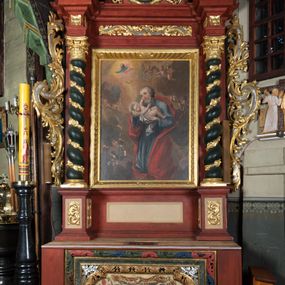 Zdjęcie nr 1: Ołtarz przyścienny o formach architektonicznych, jednoosiowy, jednokondygnacyjny ze zwieńczeniem; ujęty akantowymi uszami. Mensa prostopadłościenna; antepedium malowane w symetryczne motywy roślinno-kwiatowe na jasnobeżowym tle; ujęte złoconą ramą w kształcie leżącego prostokąta o wypukłych krótszych bokach. Nastawa ujęta parą kolumn umieszczonych na wysokich, prostopadłościennych postumentach. Trzony kolumn skręcone, oplecione kwiatowymi girlandami; kapitele kompozytowe, złocone. W polu ołtarza złocona, profilowana rama w kształcie stojącego prostokąta, mieszcząca obraz z przedstawieniem św. Józefa. Kolumny dźwigają pełne belkowanie przełamane na osiach podpór oraz odcinki trójkątnego przyczółka, na których pełnoplastyczne figurki aniołów. W partii fryzu złocony ornament akantowy oraz rozetki. Zwieńczenie w kształcie równoramiennego trapezu o wklęsłych bokach, zamknięte od góry gzymsem wklęsło-wypukłym. W polu owalna, złocona rama w formie wieńca laurowego mieszcząca obraz przedstawiający św. Jana Ewangelistę, ponad którym owalny, akantowy kartusz z napisem „IN / HONOREM S(ANCTI) JOSEPHI / ANNO DOMINI 1528”. Nastawa ujęta ażurowymi, złoconymi i srebrzonymi uszami utworzonymi z suchego akantu. Struktura ołtarza marmoryzowana w odcieniach czerwieni; dekoracja snycerska srebrzona i złocona, trzony kolumn czarne.
