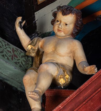 Zdjęcie nr 12: Ołtarz przyścienny o formach architektonicznych, jednoosiowy, jednokondygnacyjny ze zwieńczeniem; ujęty akantowymi uszami. Mensa prostopadłościenna; antepedium malowane w symetryczne motywy roślinno-kwiatowe na jasnobeżowym tle; ujęte złoconą ramą w kształcie leżącego prostokąta o wypukłych krótszych bokach. Nastawa ujęta parą kolumn umieszczonych na wysokich, prostopadłościennych postumentach. Trzony kolumn skręcone, oplecione kwiatowymi girlandami; kapitele kompozytowe, złocone. W polu ołtarza złocona, profilowana rama w kształcie stojącego prostokąta, mieszcząca obraz z przedstawieniem św. Józefa. Kolumny dźwigają pełne belkowanie przełamane na osiach podpór oraz odcinki trójkątnego przyczółka, na których pełnoplastyczne figurki aniołów. W partii fryzu złocony ornament akantowy oraz rozetki. Zwieńczenie w kształcie równoramiennego trapezu o wklęsłych bokach, zamknięte od góry gzymsem wklęsło-wypukłym. W polu owalna, złocona rama w formie wieńca laurowego mieszcząca obraz przedstawiający św. Jana Ewangelistę, ponad którym owalny, akantowy kartusz z napisem „IN / HONOREM S(ANCTI) JOSEPHI / ANNO DOMINI 1528”. Nastawa ujęta ażurowymi, złoconymi i srebrzonymi uszami utworzonymi z suchego akantu. Struktura ołtarza marmoryzowana w odcieniach czerwieni; dekoracja snycerska srebrzona i złocona, trzony kolumn czarne.
