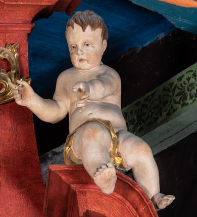 Zdjęcie nr 6: Ołtarz przyścienny o formach architektonicznych; jednoosiowy, jednokondygnacyjny ze zwieńczeniem, uszaty. Mensa prostopadłościenna; antepedium malowane z trzema kwiatowymi medalionami mieszczącymi literę J, monogram maryjny oraz literę A na jasnobeżowym tle. Poniżej środkowego medalionu płonące serce przebite krzyżem i kotwicą. W predelli nisza w kształcie poziomego prostokąta z wypukłymi krótszymi bokami, zapewne pierwotnie mieszcząca niezachowany obraz. Nastawa ujęta parą kolumn umieszczonych na wysokich, prostopadłościennych postumentach. Trzony kolumn skręcone, oplecione kwiatowymi girlandami; kompozytowe kapitele złocone. W polu ołtarza złocona, profilowana rama w kształcie pionowego prostokąta mieszcząca obraz z przedstawieniem św. Anny, św. Joachima i Marii. Kolumny dźwigają pełne belkowanie przełamane na osiach podpór oraz odcinki zbudowanego z wolut przyczółka, na których umieszczono pełnoplastyczne figurki aniołów. W partii fryzu złocony ornament akantowy przepleciony srebrzoną wstęgą  oraz rozetki. Zwieńczenie w kształcie trapezu równoramiennego o wklęsłych bokach, zamknięte od góry gzymsem w formie łuku nadwieszonego. W polu owalna, złocona rama w kształcie wieńca laurowego mieszcząca obraz przedstawiający św. Sebastiana, ponad którym akantowy kartusz owalny z inskrypcją „IN HONOREM S(ANCTI) JOACHIM ANNO DOMINI 1518”. Nastawa ujęta ażurowymi, złoconymi i srebrzonymi uszami utworzonymi z suchego akantu oraz karbowanej wstęgi. Struktura ołtarza „marmoryzowana” w odcieniach czerwieni; dekoracja snycerska srebrzona i złocona, trzony kolumn czarne.



