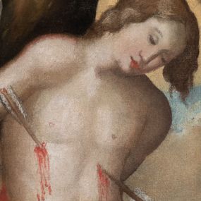 Zdjęcie nr 1: Obraz w kształcie pionowego owalu przedstawia św. Sebastiana w chwili męczeństwa. Postać świętego ukazana od połowy ud, w ujęciu trzy czwarte, zwrócona w prawo. Święty przedstawiony na tle pnia drzewa, ręce skrępowane z tyłu, tors nagi, przebity dwiema strzałami, głowa pochylona do dołu. Twarz postaci młodzieńcza, o delikatnych rysach, pozbawiona zarostu. Włosy świętego jasnobrązowe, lekko falowane, miękko okalające twarz. Oczy zamknięte. Głowa otoczona nimbem. Wokół bioder postaci luźno udrapowana czerwona tkanina odsłaniająca uda. Prawe udo przebite strzałą. Na dalszym planie przedstawione obłoki na tle błękitnego nieba. Kolorystyka obrazu ciepła, stonowana. Dzieło ujmuje złocona rama zdobiona motywem kampanul oraz akantowych wolut.
