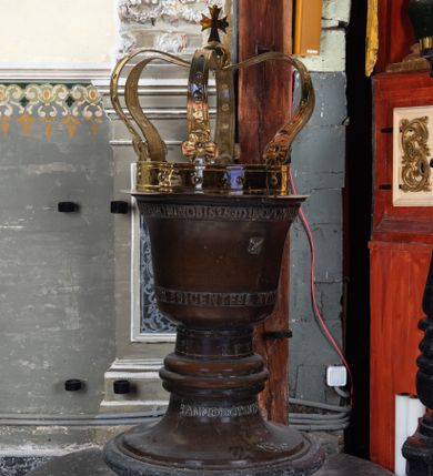 Zdjęcie nr 1: Wykonana z miedzi pokrywa chrzcielnicy  ma kształt korony królewskiej. Obręcz i  kabłąki korony wykonane z płaskownika z profilowanymi brzegami, zdobione  trybowanymi, półokrągłymi guzami. U nasady kabłąków kwiaty o czterech płatkach. Korona zwieńczona jabłkiem z krzyżem maltańskim. Na obręczy korony jest inskrypcja „X(iądz) Benedykt Parszywka Karmelita Bosy z Czerny Ofiarowal R(oku) 1852”. 