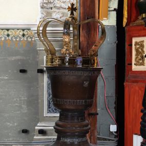 Zdjęcie nr 1: Wykonana z miedzi pokrywa chrzcielnicy  ma kształt korony królewskiej. Obręcz i  kabłąki korony wykonane z płaskownika z profilowanymi brzegami, zdobione  trybowanymi, półokrągłymi guzami. U nasady kabłąków kwiaty o czterech płatkach. Korona zwieńczona jabłkiem z krzyżem maltańskim. Na obręczy korony jest inskrypcja „X(iądz) Benedykt Parszywka Karmelita Bosy z Czerny Ofiarowal R(oku) 1852”. 