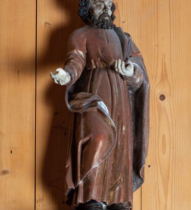 Zdjęcie nr 1: Rzeźba pełnoplastyczna, ścięta z tyłu, ustawiona na niewielkiej, prostopadłościennej podstawie. Święty Piotr został ukazany w całej postaci, frontalnie, w postawie stojącej, w nieznacznym kontrapoście, z prawą nogą wysuniętą do przodu i tułowiem odchylonym lekko w lewo. Obie ręce ugięte w łokciu i wysunięte do przodu w geście prezentowania. Piotr przedstawiony jako dojrzały, brodaty mężczyzna o ciemnych włosach i zaroście. Twarz postaci z szerokim i wysokim czołem oraz o wyraźnie zaznaczonych kościach policzkowych. Dłuższe włosy falowane, zaczesane na boki. Broda krótka, kędzierzawa. Głęboko osadzone małe oczy, ponad którymi łukowate, wyraźnie zaakcentowane brwi. Wzrok postaci skierowany przed siebie. Nos niewielki, prosty, usta małe. Święty ubrany jest w długą, złotą szatę przewiązaną w pasie oraz srebrny płaszcz luźno przewieszony przez lewe ramię postaci. Spod szat widoczne stopy w obuwiu o zaokrąglonych noskach.