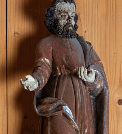 Zdjęcie nr 2: Rzeźba pełnoplastyczna, ścięta z tyłu, ustawiona na niewielkiej, prostopadłościennej podstawie. Święty Piotr został ukazany w całej postaci, frontalnie, w postawie stojącej, w nieznacznym kontrapoście, z prawą nogą wysuniętą do przodu i tułowiem odchylonym lekko w lewo. Obie ręce ugięte w łokciu i wysunięte do przodu w geście prezentowania. Piotr przedstawiony jako dojrzały, brodaty mężczyzna o ciemnych włosach i zaroście. Twarz postaci z szerokim i wysokim czołem oraz o wyraźnie zaznaczonych kościach policzkowych. Dłuższe włosy falowane, zaczesane na boki. Broda krótka, kędzierzawa. Głęboko osadzone małe oczy, ponad którymi łukowate, wyraźnie zaakcentowane brwi. Wzrok postaci skierowany przed siebie. Nos niewielki, prosty, usta małe. Święty ubrany jest w długą, złotą szatę przewiązaną w pasie oraz srebrny płaszcz luźno przewieszony przez lewe ramię postaci. Spod szat widoczne stopy w obuwiu o zaokrąglonych noskach.