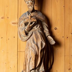 Zdjęcie nr 1: Figura drążona, ustawiona na niewielkiej podstawie. Święty został ukazany w całej postaci, w postawie stojącej, w wyraźnym kontrapoście, z prawą nogą wysuniętą do przodu. Głowa postaci zwrócona jest w trzech czwartych w prawo, wzrok skierowany przed siebie. Twarz świętego szczupła, pociągła z krótkim nosem, niewielkimi ustami oraz kędzierzawą brodą. W prawej zgiętej w łokciu ręce święty podtrzymuje otwartą księgę, na której znajdują się trzy kule. Lewa ręka postaci opuszczona wzdłuż tułowia. Święty ubrany jest w długą, obficie fałdowaną suknię oraz spięty pod szyją płaszcz. Na jego głowie znajduje się infuła biskupia. 