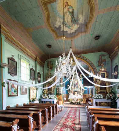 Zdjęcie nr 1: Polichromia w postaci kompozycji figuralnych zajmuje powierzchnię stropu korpusu nawowego i prezbiterium. Pośrodku stropu nawy znajduje się pole w kształcie stojącego prostokąta, którego boki mają formę półkolistych i odcinkowych łuków nadwieszonych, ujęte jest iluzjonistyczną, polichromowaną profilowaną ramą z motywem plecionki. W środku wizerunek Matki Boskiej Niepokalanie Poczętej. Zwrócona w trzech czwartych w prawo Maria stoi na obłokach z sierpem księżyca pod nogami. Sylwetka w S-kształtnym układzie. Owalną twarz charakteryzują delikatne rysy i półprzymknięte oczy. Długie, falowane włosy opadają na ramiona i plecy. Maria ma na sobie białą suknię i błękitny, rozwiany płaszcz przerzucony przez lewe ramię. Ręce złożone w geście modlitwy. Głowę ujmuje świetlisty nimb. Pozostała powierzchnia stropu podzielona różowymi pasami na 4 pola pomalowane w kolorze błękitnym i pokryte złotymi gwiazdami.
Polichromia stopu prezbiterium w postaci pól wydzielonych na rzucie dużego, równoramiennego krzyża o rozszerzających się ramionach, linia obramienia w formie stylizowanej wici roślinnej z kwiatami. Pole środkowe w kształcie koła. W każde z ramion wpisana sylwetka siedzącego na obłoku anioła w układzie frontalnym. Charakteryzują ich twarze o młodzieńczych rysach, długie, falowane włosy opadające na ramiona. Białe suknie obszyte złotymi galonami oraz osłaniające nogi płaszcze w kolorach czerwonym, zielonym i żółtym. Głowy okalają promieniste nimby. Na plecach wielobarwne skrzydła a w dłoniach rozłożone banderole z napisami – anioł od strony północnej „NAZAREŃSKI SLICZNY KOŚCIELE”, południowej „PRZYJDŹ DUCHU STWORZYCIELU”, wschodniej „ŚWIĘTY ŚWIĘTY ŚWIĘTY”, zachodniej „BOŻE OJCZE TWOJE DZIECI”. Pomiędzy polami z aniołami rodzaj 4 katuszy o szafirowych tłach z motywami: lilii z wieńcem różanym, gorejącego serca z kotwicą, skrzyżowane gałązki palmowe koroną nad nimi i gwiazdą u dołu oraz skrzyżowane klucze z monogramem imienia Jezus i 3 gwoźdźmi. Całość na błękitnym tle pokrytym złotymi gwiazdami ujęta bordiurą w formie stylizowanej wici roślinnej z naprzemiennie żółtymi i czerwonymi kwiatami. Na zakończeniu prezbiterium motyw polichromowanej konchy zdobionej gałązkami różanymi i uskrzydlonymi główkami aniołków naprzemiennie z dużymi kwiatami białych irysów. Kolorystyka polichromii zróżnicowana o żywej, nasyconej gamie.   
