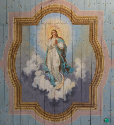 Zdjęcie nr 2: Polichromia w postaci kompozycji figuralnych zajmuje powierzchnię stropu korpusu nawowego i prezbiterium. Pośrodku stropu nawy znajduje się pole w kształcie stojącego prostokąta, którego boki mają formę półkolistych i odcinkowych łuków nadwieszonych, ujęte jest iluzjonistyczną, polichromowaną profilowaną ramą z motywem plecionki. W środku wizerunek Matki Boskiej Niepokalanie Poczętej. Zwrócona w trzech czwartych w prawo Maria stoi na obłokach z sierpem księżyca pod nogami. Sylwetka w S-kształtnym układzie. Owalną twarz charakteryzują delikatne rysy i półprzymknięte oczy. Długie, falowane włosy opadają na ramiona i plecy. Maria ma na sobie białą suknię i błękitny, rozwiany płaszcz przerzucony przez lewe ramię. Ręce złożone w geście modlitwy. Głowę ujmuje świetlisty nimb. Pozostała powierzchnia stropu podzielona różowymi pasami na 4 pola pomalowane w kolorze błękitnym i pokryte złotymi gwiazdami.
Polichromia stopu prezbiterium w postaci pól wydzielonych na rzucie dużego, równoramiennego krzyża o rozszerzających się ramionach, linia obramienia w formie stylizowanej wici roślinnej z kwiatami. Pole środkowe w kształcie koła. W każde z ramion wpisana sylwetka siedzącego na obłoku anioła w układzie frontalnym. Charakteryzują ich twarze o młodzieńczych rysach, długie, falowane włosy opadające na ramiona. Białe suknie obszyte złotymi galonami oraz osłaniające nogi płaszcze w kolorach czerwonym, zielonym i żółtym. Głowy okalają promieniste nimby. Na plecach wielobarwne skrzydła a w dłoniach rozłożone banderole z napisami – anioł od strony północnej „NAZAREŃSKI SLICZNY KOŚCIELE”, południowej „PRZYJDŹ DUCHU STWORZYCIELU”, wschodniej „ŚWIĘTY ŚWIĘTY ŚWIĘTY”, zachodniej „BOŻE OJCZE TWOJE DZIECI”. Pomiędzy polami z aniołami rodzaj 4 katuszy o szafirowych tłach z motywami: lilii z wieńcem różanym, gorejącego serca z kotwicą, skrzyżowane gałązki palmowe koroną nad nimi i gwiazdą u dołu oraz skrzyżowane klucze z monogramem imienia Jezus i 3 gwoźdźmi. Całość na błękitnym tle pokrytym złotymi gwiazdami ujęta bordiurą w formie stylizowanej wici roślinnej z naprzemiennie żółtymi i czerwonymi kwiatami. Na zakończeniu prezbiterium motyw polichromowanej konchy zdobionej gałązkami różanymi i uskrzydlonymi główkami aniołków naprzemiennie z dużymi kwiatami białych irysów. Kolorystyka polichromii zróżnicowana o żywej, nasyconej gamie.   
