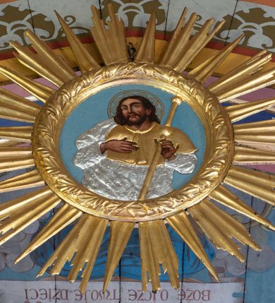 Zdjęcie nr 3: Polichromia w postaci kompozycji figuralnych zajmuje powierzchnię stropu korpusu nawowego i prezbiterium. Pośrodku stropu nawy znajduje się pole w kształcie stojącego prostokąta, którego boki mają formę półkolistych i odcinkowych łuków nadwieszonych, ujęte jest iluzjonistyczną, polichromowaną profilowaną ramą z motywem plecionki. W środku wizerunek Matki Boskiej Niepokalanie Poczętej. Zwrócona w trzech czwartych w prawo Maria stoi na obłokach z sierpem księżyca pod nogami. Sylwetka w S-kształtnym układzie. Owalną twarz charakteryzują delikatne rysy i półprzymknięte oczy. Długie, falowane włosy opadają na ramiona i plecy. Maria ma na sobie białą suknię i błękitny, rozwiany płaszcz przerzucony przez lewe ramię. Ręce złożone w geście modlitwy. Głowę ujmuje świetlisty nimb. Pozostała powierzchnia stropu podzielona różowymi pasami na 4 pola pomalowane w kolorze błękitnym i pokryte złotymi gwiazdami.
Polichromia stopu prezbiterium w postaci pól wydzielonych na rzucie dużego, równoramiennego krzyża o rozszerzających się ramionach, linia obramienia w formie stylizowanej wici roślinnej z kwiatami. Pole środkowe w kształcie koła. W każde z ramion wpisana sylwetka siedzącego na obłoku anioła w układzie frontalnym. Charakteryzują ich twarze o młodzieńczych rysach, długie, falowane włosy opadające na ramiona. Białe suknie obszyte złotymi galonami oraz osłaniające nogi płaszcze w kolorach czerwonym, zielonym i żółtym. Głowy okalają promieniste nimby. Na plecach wielobarwne skrzydła a w dłoniach rozłożone banderole z napisami – anioł od strony północnej „NAZAREŃSKI SLICZNY KOŚCIELE”, południowej „PRZYJDŹ DUCHU STWORZYCIELU”, wschodniej „ŚWIĘTY ŚWIĘTY ŚWIĘTY”, zachodniej „BOŻE OJCZE TWOJE DZIECI”. Pomiędzy polami z aniołami rodzaj 4 katuszy o szafirowych tłach z motywami: lilii z wieńcem różanym, gorejącego serca z kotwicą, skrzyżowane gałązki palmowe koroną nad nimi i gwiazdą u dołu oraz skrzyżowane klucze z monogramem imienia Jezus i 3 gwoźdźmi. Całość na błękitnym tle pokrytym złotymi gwiazdami ujęta bordiurą w formie stylizowanej wici roślinnej z naprzemiennie żółtymi i czerwonymi kwiatami. Na zakończeniu prezbiterium motyw polichromowanej konchy zdobionej gałązkami różanymi i uskrzydlonymi główkami aniołków naprzemiennie z dużymi kwiatami białych irysów. Kolorystyka polichromii zróżnicowana o żywej, nasyconej gamie.   
