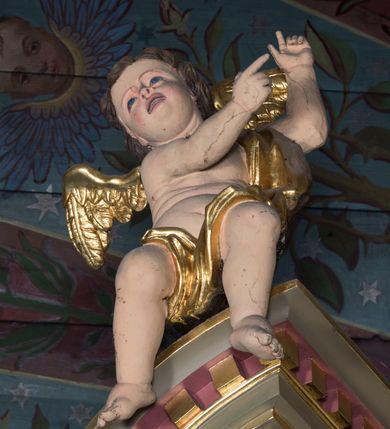 Zdjęcie nr 14: Ołtarz architektoniczny, jednokondygnacyjny, jednoosiowy ze zwieńczeniem. Ołtarz prostopadłościenny, z drewnianą mensą. Antepedium ujęte szerokim obramieniem, pośrodku w polu w kształcie koła złocony monogram imienia Jezus. Retabulum osadzone na zryzalitowanym po bokach cokole, ujętym parą wolutowych impostów. Część środkowa flankowana parą kolumn wspierających niepełne, wyłamujące się ponad nimi, przerwane w partii fryzu belkowanie. Zwieńczenie ujęte parą spływów wolutowych, zamknięte fragmentem gzymsu w postaci półkolistego łuku nadwieszonego, po bokach przerwany, półkolisty przyczółek. Pola cokołu zdobione motywami wici roślinnej. W dolnej części pola środkowego nastawy kwietna girlanda, wyżej, po bokach para aniołków, w górnej partii pośrodku gzymsu kartusz z napisem „OTO BARANEK BOŻY” z podwieszeniem w formie podwiązanej w narożach polach kotary. W partiach fryzu rozety. W zwieńczeniu motyw płaskorzeźbionej Baranka Paschalnego ujętego promienistą glorią. Dolną część spływów wolutowych zdobią liście akantu. Szczyt w formie krzyża osadzonego na ażurowej podstawie w postaci wici akantowej, ujęty parą płomienistych wazonów. Na przerwanym przyczółku para figur siedzących aniołków. Pole części środkowej retabulum w kształcie zbliżonym do kwadratu, zamkniętym półkoliście, ujętym rzeźbioną, złoconą ramą. W środku obraz „Trójcy Świętej”. Po bokach retabulum para rzeźb, po lewej św. Jakub, po prawej św. Józef. Struktura polichromowana w kolorze zielonym i niebieskim, detal architektoniczny złocony i srebrzony.   