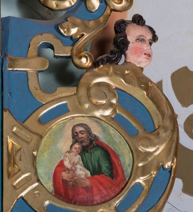 Zdjęcie nr 12: Ołtarz architektoniczny, jednokondygnacyjny, jednoosiowy ze zwieńczeniem. Ołtarz prostopadłościenny, o przednich narożach ujętych pilastrami hermowymi, z drewniana mensą. Antepedium w formie prostokątnej płyciny z płaskorzeźbionym medalionem z monogramem maryjnym okolonym drobnymi promieniami i ujętym liśćmi i kwiatami narcyza. Retabulum osadzone na niewysokim cokole, lekko zryzalitowanym po bokach. Wyżej predella ujęta parą konsoli wolutowych wspierających wyłamujący się ponad nimi gzyms. Cokół wraz z predellą flankowany parą uszaków w formie spływów wolutowych. Część środkowa ujęta parą kolumn o trzonach zdobionych motywem kandelabru, wspierających fryz wyłamujący się ponad nimi oraz gzyms przybierające postać trójboczną. Zwieńczenie w kształcie kwadratu zamkniętego odcinkiem gzymsu o lekko zryzalitowanych bokach. Predellę, część środkową i zwieńczenie ujmują pary ujmują pary uszaków o fantazyjnych wykrojach, zdobione ornamentem okuciowym i wicią roślinną. Uszaki zwieńczenia dodatkowo zdobione parą główek anielskich i medalionów ze św. Józefem po prawej stronie i św. Zofią po lewej. Na bokach gzymsu para figur siedzących aniołów. Szczyt w postaci ujętego parą wolut i zwieńczonego krzyżem kartusza z okrągłym  medalionem z monogramem maryjnym. w predelli obraz w kształcie leżącego prostokąta ze sceną Zwiastowania. Pole środkowe retabulum, ujęte motywami kaboszonów, ma kształt stojącego prostokąta zamkniętego półkolistym łukiem nadwieszonym, w środku obraz Madonny z Dzieciątkiem. W zwieńczeniu obraz w kształcie stojącego prostokąta, ujęty szeroką ramą z uszakami w narożach, zdobioną ornamentem. W środku wizerunek Matki Boskiej Różańcowej ze św. Dominikiem. Struktura polichromowana w odcieniach koloru niebieskiego, detal architektoniczny i ornamentyka złocone i srebrzone.      