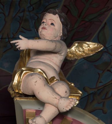 Zdjęcie nr 3: Pełnoplastyczne, całopostaciowe figury aniołów siedzących w zdynamizowanych pozach na przerwanym przyczółku ołtarza głównego, ukazanych pod postaciami małych dzieci. Anioł po prawej stronie retabulum siedząc zwrócony na wprost odwraca się w trzech czwartych w prawo lekko pochylając do przodu. Zaokrągloną twarz charakteryzują pełne, dziecięce rysy o wąskich łukach brwi, dużych, migdałowatych oczach, lekko zadartym nosie, kształtnych ustach i podbródku. Naga sylwetka o zaokrąglonych kształtach, z dwoma fałdkami nad brzuchem osłonięta jest w partii bioder złoconą szatą zarzuconą przez prawe ramię. Wyciągnięta do przodu lewa ręka skierowana jest w prawo, nogi skrzyżowane. Na plecach rozłożone złocone skrzydła. 
Anioł po lewej stronie retabulum siedząc zwrócony na wprost odwraca się w trzech czwartych w prawo lekko odchylając nieco do tyłu sylwetkę. Zaokrągloną twarz charakteryzują pełne, dziecięce rysy o wąskich łukach brwi, dużych, migdałowatych oczach, zadartym nosie, rozchylonych ustach i wydatnym podbródku. Naga sylwetka o zaokrąglonych kształtach, z dwoma fałdkami nad brzuchem osłonięta jest w partii bioder złoconą szatą zarzuconą przez lewe ramię. Skierowane w lewo, zgięte w łokciach ręce uniesione są do góry z wyprostowanymi palcami wskazujacymi. Na plecach rozłożone złocone skrzydła. 
