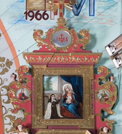 Zdjęcie nr 4: Ołtarz architektoniczny, jednokondygnacyjny, jednoosiowy ze zwieńczeniem. Ołtarz prostopadłościenny, o przednich narożach ujętych pilastrami hermowymi, z drewniana mensą. Antepedium w formie prostokątnej płyciny z płaskorzeźbionym motywem hostii okolonej drobnymi promieniami i ujętej liśćmi i pąkami mniszka lekarskiego.  Retabulum osadzone na niewysokim cokole, lekko zryzalitowanym po bokach. Wyżej predella ujęta parą konsoli wolutowych wspierających wyłamujący się ponad nimi gzyms. Cokół wraz z predellą flankowany parą uszaków w formie spływów wolutowych. Część środkowa ujęta parą kolumn o trzonach zdobionych motywem kandelabru, wspierających fryz wyłamujący się ponad nimi oraz gzyms przybierające postać trójboczną. Zwieńczenie w kształcie kwadratu zamkniętego odcinkiem gzymsu o lekko zryzalitowanych bokach. Predellę, część środkową i zwieńczenie ujmują pary ujmują pary uszaków o fantazyjnych wykrojach, zdobione ornamentem okuciowym i wicią roślinną. Uszaki zwieńczenia dodatkowo zdobione parą główek anielskich i medalionów ze św. Barbarą po prawej stronie i św. Katarzyną Aleksandryjską po lewej. Na bokach gzymsu para figur siedzących aniołów. Szczyt w postaci ujętego parą wolut i zwieńczonego krzyżem kartusza z okrągłym  medalionem z monogramem imienia Jezus. w predelli obraz w kształcie leżącego prostokąta ze sceną Nawiedzenie św. Elżbiety. Pole środkowe retabulum, ujęte motywami kaboszonów, ma kształt stojącego prostokąta zamkniętego półkolistym łukiem nadwieszonym, w środku obraz Najświętszego Serca Jezusa. W zwieńczeniu obraz w kształcie stojącego prostokąta, ujęty szeroką ramą z uszakami w narożach, zdobioną ornamentem. W środku wizerunek Matki Boskiej Różańcowej ze św. Teresą z Avila. Struktura polichromowana w odcieniach brązu, detal architektoniczny i ornamentyka złocone i srebrzone.      