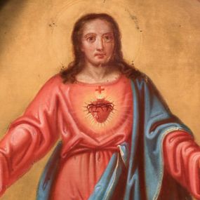 Zdjęcie nr 1: Obraz w kształcie stojącego prostokąta zamkniętego półkolistym łukiem nadwieszonym, z całopostaciowym wizerunkiem Najświętszego Serca Jezusa. Zwrócony na wprost Jezus stoi na obłokach w lekkim kontrapoście. Nieznacznie skierowaną w lewo głowę charakteryzuje owalna twarz o delikatnych rysach z dużymi, wpatrzonymi przed siebie oczami, długim nosem, kształtnymi ustami i krótkim zarostem. Długie, falowane włosy opadają na ramiona. Jezus ubrany jest w długą, czerwoną, przewiązaną w pasie czerwonym sznurem suknię i niebieski płaszcz przerzucony przez lewe ramię i przełożony przez sznur sukni oraz obszyty wąskim, złoconym galonem. Ręce są opuszczone w dół, lekko rozchylone na boki, na dłoniach i stopach widoczne ślady ran. Pośrodku klatki piersiowej gorejące serce ujęte promienistą glorią. Wokół głowy Jezusa ślad po aplikowanym nimbie. Tło w odcieniach ochry. 