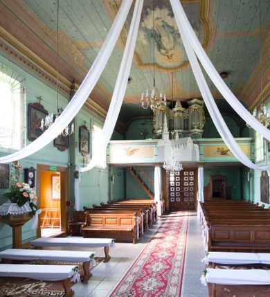 Zdjęcie nr 4: Prospekt organowy o formach architektonicznych, pięcioosiowy, jednokondygnacyjny ze zwieńczeniem. Osie nieparzyste wypukłe; osie skrajne na rzucie trójkąta; oś środkowa niższa na rzucie półkola ujęta w górnej części odwróconymi rogami obfitości. W osiach parzystych niższe płyciny mieszczące mniejsze piszczałki ujęte od góry parą stykających się wolut akantowych. W górnej partii części piszczałkowej osi nieparzystych płaskorzeźbiona dekoracja akantowa. Zwieńczenie utworzone z przełamującego się belkowania. W osi środkowej szczyt w postaci krzyża ujętego parą wolut akantowych. Struktura malowana w odcieniach popielu i jasnej zieleni, ornamenty złocone i srebrzone. Parapet chóru muzycznego w formie pełnej balustrady artykułowanej 4 pilastrami wspierającymi wyłamujący się ponad nimi gzyms wieńczący, wspartej na 4 drewnianych słupach. W polu po lewej stronie polichromowana kompozycja ze skrzypiec zestawionych z gałązką laurową i zwojem papieru nutowego. W płycinie po prawej stronie analogiczna kompozycja z lutnią zamiast skrzypiec. Struktura parapetu polichromowana w pastelowych odcieniach zieleni, błękitu, niebieskiego, brązu i bieli.  