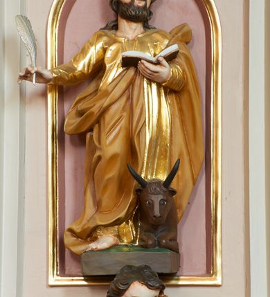 Zdjęcie nr 3: Ambona przyścienna, wisząca, z dostępem w postaci jednobiegowych schodów z pełną balustradą, dostawionych od północy. Kosz na planie ośmioboku, ustawiony na niskim, profilowanym cokole, z podwieszeniem w formie zbliżonej do spłaszczonego stożka, o wklęsło-wypukłych ściankach, zakończonego szyszką. Ścianki ambony wydzielone zwielokrotnionymi pilastrami toskańskimi, z płycinami w partii trzonów, podtrzymującymi przełamujący się nad nimi gzyms tworzący parapet. W polach płyciny w formie stojącego prostokąta zamkniętego łukiem półkolistym z figurami czterech ewangelistów ustawionych na wspornikach w postaci uskrzydlonych główek anielskich. Baldachim na planie ośmioboku, w formie zbliżonej do spłaszczonego stożka, o wklęsło-wypukłych ściankach, o krawędzi obwiedzionej lambrekinem, zakończonego postumentem z figurą Chrystusa w typie Salvator Mundi. Na podniebieniu gołębica Ducha Świętego w glorii promienistej. Struktura polichromowana w odcieniach beżu, z bladoróżowymi detalami i złoconymi profilami. Figury ewangelistów i Chrystusa ścięte z tyłu, ukazane frontalnie, w kontrapostach. Twarze mają pociągłe, o migdałowatych oczach, garbatych nosach i pełnych ustach, okolone są gęstymi, krótkimi brodami i falowanymi włosami opadającymi na ramiona. Postacie ubrane są w złocone tuniki przepasane w talii oraz płaszcze. Ewangeliści trzymają w rękach pióra i otwarte księgi, przy nogach znajdują się ich atrybuty. Chrystus w lewej ręce trzyma jabłko królewskie, prawą błogosławi. 