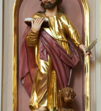 Zdjęcie nr 2: Ambona przyścienna, wisząca, z dostępem w postaci jednobiegowych schodów z pełną balustradą, dostawionych od północy. Kosz na planie ośmioboku, ustawiony na niskim, profilowanym cokole, z podwieszeniem w formie zbliżonej do spłaszczonego stożka, o wklęsło-wypukłych ściankach, zakończonego szyszką. Ścianki ambony wydzielone zwielokrotnionymi pilastrami toskańskimi, z płycinami w partii trzonów, podtrzymującymi przełamujący się nad nimi gzyms tworzący parapet. W polach płyciny w formie stojącego prostokąta zamkniętego łukiem półkolistym z figurami czterech ewangelistów ustawionych na wspornikach w postaci uskrzydlonych główek anielskich. Baldachim na planie ośmioboku, w formie zbliżonej do spłaszczonego stożka, o wklęsło-wypukłych ściankach, o krawędzi obwiedzionej lambrekinem, zakończonego postumentem z figurą Chrystusa w typie Salvator Mundi. Na podniebieniu gołębica Ducha Świętego w glorii promienistej. Struktura polichromowana w odcieniach beżu, z bladoróżowymi detalami i złoconymi profilami. Figury ewangelistów i Chrystusa ścięte z tyłu, ukazane frontalnie, w kontrapostach. Twarze mają pociągłe, o migdałowatych oczach, garbatych nosach i pełnych ustach, okolone są gęstymi, krótkimi brodami i falowanymi włosami opadającymi na ramiona. Postacie ubrane są w złocone tuniki przepasane w talii oraz płaszcze. Ewangeliści trzymają w rękach pióra i otwarte księgi, przy nogach znajdują się ich atrybuty. Chrystus w lewej ręce trzyma jabłko królewskie, prawą błogosławi. 