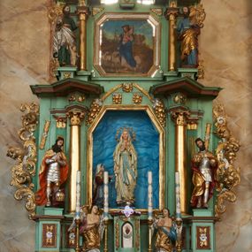 Zdjęcie nr 1: Nastawa ołtarzowa architektoniczna, jednoosiowa, dwukondygnacyjna na cokole z wyodrębnionymi dwoma prostopadłościanami. Ołtarz prostopadłościenny, zwężający się ku dołowi, mensa drewniana. Antepedium marmoryzowane z iluzjonistycznie malowanymi płycinami. Tabernakulum w formie drewnianej skrzynki, półkoliście wybrzuszone od frontu, zakończone profilowanym gzymsem. Drzwiczki o kształcie stojącego prostokąta zamknięte ostrołukiem z malowanym gorejącym sercem, flankowane płaskorzeźbioną winną latoroślą. Tabernakulum ujęte dwiema figurami klęczących na obłokach aniołów. Pierwsza kondygnacja flankowana dwiema parami pilastrów, zewnętrzna o kanelowanych trzonach. Przed wewnętrzną parą stoją dwie kolumny o kapitelach kompozytowych, przed zewnętrzną ustawione są figury św. Stefana i św. Władysława. Podpory dźwigają pełne belkowanie z silnie wysuniętym gzymsem, wyłamane pod kątem w partii kolumn, przerwane pośrodku. W polu centralnym nisza w formie stojącego prostokąta o ściętych górnych narożach ujęta profilowaną ramą, z grupą rzeźbiarską Matki Boskiej z Lourdes i Bernadetą Soubirous. W górnej partii nisza dekorowana zwisami owocowo-kwiatowymi. Pierwsza kondygnacja ujęta uszami utworzonymi z akantu i karbowanej wstęgi. Druga kondygnacja flankowana parą kolumn oraz parą figur św. Marka i św. Mateusza na cokołach. Podpory dźwigają pełne belkowanie z silnie wysuniętym gzymsem, wyłamane na ich osi, przerwane nad polem środkowym. Na belkowaniu dwie figurki aniołków, pośrodku na wsporniku figura Chrystusa w glorii, pośród obłoków. W polu obraz Chrystusa Dobrego Pasterza w formie leżącego prostokąta o ściętych narożach, w ramie. Druga kondygnacja ujęta uszami utworzonymi z akantu. Struktura polichromowana w kolorze jasnozielonym, kolumny, ornamentyka i profile złocone, detal srebrzony. 

