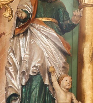 Zdjęcie nr 8: Nastawa ołtarzowa architektoniczna, jednoosiowa, dwukondygnacyjna na cokole z wyodrębnionymi dwoma prostopadłościanami. Ołtarz prostopadłościenny, zwężający się ku dołowi, mensa drewniana. Antepedium marmoryzowane z iluzjonistycznie malowanymi płycinami. Tabernakulum w formie drewnianej skrzynki, półkoliście wybrzuszone od frontu, zakończone profilowanym gzymsem. Drzwiczki o kształcie stojącego prostokąta zamknięte ostrołukiem z malowanym gorejącym sercem, flankowane płaskorzeźbioną winną latoroślą. Tabernakulum ujęte dwiema figurami klęczących na obłokach aniołów. Pierwsza kondygnacja flankowana dwiema parami pilastrów, zewnętrzna o kanelowanych trzonach. Przed wewnętrzną parą stoją dwie kolumny o kapitelach kompozytowych, przed zewnętrzną ustawione są figury św. Stefana i św. Władysława. Podpory dźwigają pełne belkowanie z silnie wysuniętym gzymsem, wyłamane pod kątem w partii kolumn, przerwane pośrodku. W polu centralnym nisza w formie stojącego prostokąta o ściętych górnych narożach ujęta profilowaną ramą, z grupą rzeźbiarską Matki Boskiej z Lourdes i Bernadetą Soubirous. W górnej partii nisza dekorowana zwisami owocowo-kwiatowymi. Pierwsza kondygnacja ujęta uszami utworzonymi z akantu i karbowanej wstęgi. Druga kondygnacja flankowana parą kolumn oraz parą figur św. Marka i św. Mateusza na cokołach. Podpory dźwigają pełne belkowanie z silnie wysuniętym gzymsem, wyłamane na ich osi, przerwane nad polem środkowym. Na belkowaniu dwie figurki aniołków, pośrodku na wsporniku figura Chrystusa w glorii, pośród obłoków. W polu obraz Chrystusa Dobrego Pasterza w formie leżącego prostokąta o ściętych narożach, w ramie. Druga kondygnacja ujęta uszami utworzonymi z akantu. Struktura polichromowana w kolorze jasnozielonym, kolumny, ornamentyka i profile złocone, detal srebrzony. 

