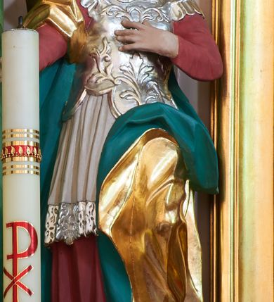 Zdjęcie nr 9: Nastawa ołtarzowa architektoniczna, dwukondygnacyjna ze zwieńczeniem, obie kondygnacje trójosiowe. Ołtarz murowany, prostopadłościenny, mensa z kamiennym portatylem. Antepedium dekorowane malowaną iluzjonistycznie prostokątną płyciną z wypukłymi krótszymi bokami. Na ołtarzu tabernakulum w formie drewnianej skrzynki ujętej kolumienkami podtrzymującymi gzyms. Do niego wbudowana drewniana skrzynka obita metalową blachą, z drzwiczkami w kształcie stojącego prostokąta, ujętego ramą, z wizerunkiem krzyża, winnego grona, kłosów zbóż i kielicha z hostią w polu. Całość flankowana uszami utworzonymi z cęg i kratki. Na tabernakulum tron wystawienia przyjmujący postać glorii promienistej, z parą aniołów unoszącą nad nią koronę zamkniętą. Tron flankowany dwoma klęczącymi aniołkami trzymającymi lichtarze ze świecami. Pierwsza kondygnacja na dwustrefowym cokole, w górnej partii z wyodrębnionymi prostopadłościanami, dekorowanymi płycinami z ornamentem roślinnym. Osie wydzielone czterema kolumnami o kapitelach kompozytowych, dźwigających pełne belkowanie z silnie wysuniętym gzymsem, wyłamane na ich osi oraz ustawione pod kątem na zewnątrz. Fryz dekorowany medalionem z monogramem IHS, uskrzydlonymi główkami anielskimi i ornamentem roślinnym. W polu środkowym wnęka w formie stojącego prostokąta, ujęta profilowaną ramą, z obrazem św. Jakuba. Wnęka flankowana figurami św. Katarzyny Aleksandryjskiej i św. Barbary ustawionymi na cokołach. Na osiach bocznych rzeźby św. Jana Chrzciciela i św. Andrzeja na cokołach. Pierwsza kondygnacja flankowana uszami utworzonymi z wici roślinnej i kratki. Druga kondygnacja na cokole z wyodrębnionymi prostopadłościanami, dekorowanymi płycinami z ornamentem roślinnym. Osie wydzielone czterema kolumnami o kapitelach kompozytowych, dźwigającymi pełne belkowanie, wyłamane na ich osi. Wewnętrzna para zwrócona pod kątem do środka, para skrajna na zewnątrz. Fryz dekorowany uskrzydlonymi główkami anielskimi. W polu obraz św. Józefa z Dzieciątkiem w formie stojącego prostokąta zamkniętego łukiem odcinkowym, ujęty profilowaną ramą. Na osiach bocznych ustawione figury niezidentyfikowanej świętej i św. Jadwigi (?). Na skraju belkowania pierwszej kondygnacji umiejscowione rzeźby Marii i św. Jana. Druga kondygnacja flankowana uszami utworzonymi z wici roślinnej. Zwieńczenie w kształcie zbliżonym do leżącego prostokąta, o wklęsłych bokach, zamkniętego łukiem odcinkowym nadwieszonym. W polu grupa rzeźbiarska Koronacji Marii, w której postacie unoszą się na obłokach, nad nimi zaś znajduje się gołębica Ducha Świętego w glorii. Na belkowaniu drugiej kondygnacji ustawione dwa klęczące na obłokach aniołki oraz figury św. Stefana i św. Władysława. Struktura polichromowana w kolorze beżowym, z bladoróżowymi detalami; kolumny malowane na sposób imitujący marmoryzacje w kolorze zielonym; profile i ornamentyka złocone. 

