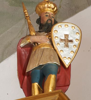 Zdjęcie nr 13: Nastawa ołtarzowa architektoniczna, dwukondygnacyjna ze zwieńczeniem, obie kondygnacje trójosiowe. Ołtarz murowany, prostopadłościenny, mensa z kamiennym portatylem. Antepedium dekorowane malowaną iluzjonistycznie prostokątną płyciną z wypukłymi krótszymi bokami. Na ołtarzu tabernakulum w formie drewnianej skrzynki ujętej kolumienkami podtrzymującymi gzyms. Do niego wbudowana drewniana skrzynka obita metalową blachą, z drzwiczkami w kształcie stojącego prostokąta, ujętego ramą, z wizerunkiem krzyża, winnego grona, kłosów zbóż i kielicha z hostią w polu. Całość flankowana uszami utworzonymi z cęg i kratki. Na tabernakulum tron wystawienia przyjmujący postać glorii promienistej, z parą aniołów unoszącą nad nią koronę zamkniętą. Tron flankowany dwoma klęczącymi aniołkami trzymającymi lichtarze ze świecami. Pierwsza kondygnacja na dwustrefowym cokole, w górnej partii z wyodrębnionymi prostopadłościanami, dekorowanymi płycinami z ornamentem roślinnym. Osie wydzielone czterema kolumnami o kapitelach kompozytowych, dźwigających pełne belkowanie z silnie wysuniętym gzymsem, wyłamane na ich osi oraz ustawione pod kątem na zewnątrz. Fryz dekorowany medalionem z monogramem IHS, uskrzydlonymi główkami anielskimi i ornamentem roślinnym. W polu środkowym wnęka w formie stojącego prostokąta, ujęta profilowaną ramą, z obrazem św. Jakuba. Wnęka flankowana figurami św. Katarzyny Aleksandryjskiej i św. Barbary ustawionymi na cokołach. Na osiach bocznych rzeźby św. Jana Chrzciciela i św. Andrzeja na cokołach. Pierwsza kondygnacja flankowana uszami utworzonymi z wici roślinnej i kratki. Druga kondygnacja na cokole z wyodrębnionymi prostopadłościanami, dekorowanymi płycinami z ornamentem roślinnym. Osie wydzielone czterema kolumnami o kapitelach kompozytowych, dźwigającymi pełne belkowanie, wyłamane na ich osi. Wewnętrzna para zwrócona pod kątem do środka, para skrajna na zewnątrz. Fryz dekorowany uskrzydlonymi główkami anielskimi. W polu obraz św. Józefa z Dzieciątkiem w formie stojącego prostokąta zamkniętego łukiem odcinkowym, ujęty profilowaną ramą. Na osiach bocznych ustawione figury niezidentyfikowanej świętej i św. Jadwigi (?). Na skraju belkowania pierwszej kondygnacji umiejscowione rzeźby Marii i św. Jana. Druga kondygnacja flankowana uszami utworzonymi z wici roślinnej. Zwieńczenie w kształcie zbliżonym do leżącego prostokąta, o wklęsłych bokach, zamkniętego łukiem odcinkowym nadwieszonym. W polu grupa rzeźbiarska Koronacji Marii, w której postacie unoszą się na obłokach, nad nimi zaś znajduje się gołębica Ducha Świętego w glorii. Na belkowaniu drugiej kondygnacji ustawione dwa klęczące na obłokach aniołki oraz figury św. Stefana i św. Władysława. Struktura polichromowana w kolorze beżowym, z bladoróżowymi detalami; kolumny malowane na sposób imitujący marmoryzacje w kolorze zielonym; profile i ornamentyka złocone. 

