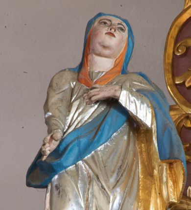 Zdjęcie nr 1: Rzeźba pełna, ustawiona na nieregularnej podstawie. Maria ukazana frontalnie, z uniesioną głową, w kontrapoście. Lewą rękę kładzie na piersi, prawą wyciąga w dół. Twarz ma pełną, z oczami skierowanymi w górę, prostym nosie i małych ustach. Wokół głowy ma pomarańczową podwikę. Ubrana jest w srebrzoną suknię oraz niebieski płaszcz ze złoconą podszewką zarzucony na głowę i ramiona. Polichromia ciała naturalistyczna.


 