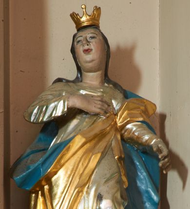 Zdjęcie nr 1: Rzeźba pełnoplastyczna, ustawiona na podstawie na planie kwadratu. Święta ukazana frontalnie, w kontrapoście, prawą rękę kładzie na piersi, lewą wyciąga w przód. Twarz ma pełną, o migdałowatych oczach, małym nosie i otwartych ustach, okoloną długimi, brązowymi włosami, opadającymi na ramiona. Na głowie ma koronę otwartą. Ubrana jest w srebrzoną suknię oraz złocony płaszcz z niebieską podszewką przewiązany diagonalnie przez lewe ramię. Polichromia w partiach ciała naturalistyczna. 
