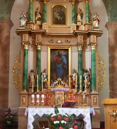 Zdjęcie nr 3: Rzeźba pełnoplastyczna, ustawiona na podstawie na planie kwadratu. Święta ukazana frontalnie, w kontrapoście, prawą rękę kładzie na piersi, lewą wyciąga w przód. Twarz ma pełną, o migdałowatych oczach, małym nosie i otwartych ustach, okoloną długimi, brązowymi włosami, opadającymi na ramiona. Na głowie ma koronę otwartą. Ubrana jest w srebrzoną suknię oraz złocony płaszcz z niebieską podszewką przewiązany diagonalnie przez lewe ramię. Polichromia w partiach ciała naturalistyczna. 
