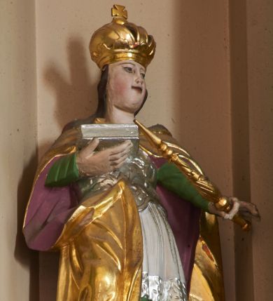 Zdjęcie nr 1: Rzeźba pełna, ustawiona na podstawie na planie kwadratu. Święta ukazana frontalnie, z głową skierowaną w lewo, w kontrapoście. Prawą, ugiętą ręką podtrzymuje zamkniętą księgę, w lewej, wyciągniętej w bok ma berło. Jej twarz jest pociągła, o pełnych policzkach, migdałowatych oczach, prostym nosie i rozchylonych ustach, okolona długimi włosami. Ubrana jest w zieloną suknię spodnią, białą szatę wierzchnią dekorowaną przy brzegu srebrzoną koronką, srebrzony gorset zdobiony płaskorzeźbionym ornamentem roślinnym. Na ramiona ma narzucony złocony płaszcz z fioletową podszewką, zapięty na piersi i zawinięty na lewym boku postaci. Polichromia naturalistyczna w partiach ciała.