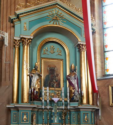 Zdjęcie nr 1: Nastawa ołtarzowa architektoniczna, jednoosiowa, jednokondygnacyjna, na cokole z wyodrębnionymi zwielokrotnionymi prostopadłościanami. Ołtarz murowany, prostopadłościenny, rozszerzający się ku górze. Mensa kamienna; antepedium marmoryzowane z iluzjonistycznie malowaną płyciną z medalionem. Cokół dekorowany płycinami z ornamentem roślinnym i kampanulami. Nastawa ujęta dwiema parami kolumn w układzie schodkowym. Wewnętrzna para podtrzymuje łuk odcinkowy, wszystkie podpory zaś trójkątny szczyt zamknięty profilowanym gzymsem z kostkowaniem, dekorowany wicią roślinną, całość zwieńczona krzyżem. Pole środkowe tworzy nisza w formie stojącego prostokąta zamkniętego łukiem odcinkowym, wewnątrz niej mniejsza płycina o kształcie stojącego prostokąta zamkniętego łukiem półkolistym, ujęta profilowaną ramą, z mniejszym obrazem Matki Boskiej Częstochowskiej, w osobnej, profilowanej ramie. Nad obrazem monogram maryjny flankowany gałązkami lilii, pod nim ornament roślinny. Po bokach wizerunku znajdują się figury św. Stanisława i św. Wojciecha ustawione na niskich cokołach. W przestrzeni szczytu wnęka o fantazyjnym kształcie z okiem Opatrzności w glorii promienistej. Struktura polichromowana w kolorze jasnozielonym, płyciny na zielono; ornamentyka, profile i kolumny złocone.