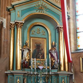 Zdjęcie nr 1: Nastawa ołtarzowa architektoniczna, jednoosiowa, jednokondygnacyjna, na cokole z wyodrębnionymi zwielokrotnionymi prostopadłościanami. Ołtarz murowany, prostopadłościenny, rozszerzający się ku górze. Mensa kamienna; antepedium marmoryzowane z iluzjonistycznie malowaną płyciną z medalionem. Cokół dekorowany płycinami z ornamentem roślinnym i kampanulami. Nastawa ujęta dwiema parami kolumn w układzie schodkowym. Wewnętrzna para podtrzymuje łuk odcinkowy, wszystkie podpory zaś trójkątny szczyt zamknięty profilowanym gzymsem z kostkowaniem, dekorowany wicią roślinną, całość zwieńczona krzyżem. Pole środkowe tworzy nisza w formie stojącego prostokąta zamkniętego łukiem odcinkowym, wewnątrz niej mniejsza płycina o kształcie stojącego prostokąta zamkniętego łukiem półkolistym, ujęta profilowaną ramą, z mniejszym obrazem Matki Boskiej Częstochowskiej, w osobnej, profilowanej ramie. Nad obrazem monogram maryjny flankowany gałązkami lilii, pod nim ornament roślinny. Po bokach wizerunku znajdują się figury św. Stanisława i św. Wojciecha ustawione na niskich cokołach. W przestrzeni szczytu wnęka o fantazyjnym kształcie z okiem Opatrzności w glorii promienistej. Struktura polichromowana w kolorze jasnozielonym, płyciny na zielono; ornamentyka, profile i kolumny złocone.