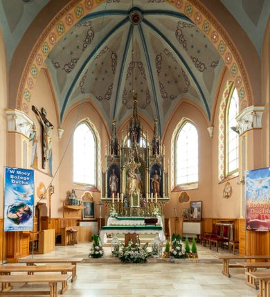 Zdjęcie nr 5: Ołtarz przyścienny, architektoniczny, trójosiowy, jednokondygnacyjny ze zwieńczeniem. Mensa skrzyniowa, prostopadłościenna. Na niej dwukondygnacyjne tabernakulum. W dolnej partii dekorowane postacia Baranka Apokaliptycznego drzwiczki ujęte otrołukowymi niszami wypełnionymi pękami kłosó. W drugiej kondygnacji tron wystawienia z niszą zdobioną rozetami i monogramem „IHS”, zwieńczoną nadwieszonymi łukami w ośli grzbiet z pinaklami i kwiatonami i ujętą parą klęczących aniołów. Predella wysoka, dekorowana fryzem arkadkowym, ostrołukowym, wypełnionym fragmentami wili winnej latorośli. W pierwszej kondygnacji retabulum trzy nisze prostokątne zamknięte od góry wimpergą na tle szczytu, ujete pinaklami wspartymi na służkach. Środkowa nisza wyższa i szersza od bocznych, rama dekorowana wyschniętą wicią roślinną, wszystkie zdobione ażurowym ornamentem ostrołukowym i żabkami; szczyty dekoruje fryz z rombami wypełnionymi czworoliśćmi.  Boczne nisze zwieńczone ustawionymi skośnie ażurowymi kapliczkami z pinaklami, zdobionymi żabkami i kwiatonami z rzeźbą mężczyzny z wiosłem po lewej i kobiety z lilią po prawej stronie. W środkowej niszy kondygnacji płaskorzeźbiona scena Nawiedzenia Najświętszej Marii Panny, w bocznych postać starego mężczyzny z kadzielnicą i św. Jan Chrzciciel. Kondygnacja ujęta uszakami utworzonymi z przypór z blendami i pinaklami. W zwieńczeniu ażurowa kapliczka powtarzająca kształt kapliczek wieńczących osie boczne pierwszej kondygnacji z niszą, w której figura św. Józefa z Dzieciątkiem. 
Struktura jasnozielona, nisze niebieskie, fragmenty dekoracji czerwone i niebieskie, detale złocone. 
