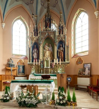 Zdjęcie nr 3: Ołtarz przyścienny, architektoniczny, trójosiowy, jednokondygnacyjny ze zwieńczeniem. Mensa skrzyniowa, prostopadłościenna. Na niej dwukondygnacyjne tabernakulum. W dolnej partii dekorowane postacia Baranka Apokaliptycznego drzwiczki ujęte otrołukowymi niszami wypełnionymi pękami kłosó. W drugiej kondygnacji tron wystawienia z niszą zdobioną rozetami i monogramem „IHS”, zwieńczoną nadwieszonymi łukami w ośli grzbiet z pinaklami i kwiatonami i ujętą parą klęczących aniołów. Predella wysoka, dekorowana fryzem arkadkowym, ostrołukowym, wypełnionym fragmentami wili winnej latorośli. W pierwszej kondygnacji retabulum trzy nisze prostokątne zamknięte od góry wimpergą na tle szczytu, ujete pinaklami wspartymi na służkach. Środkowa nisza wyższa i szersza od bocznych, rama dekorowana wyschniętą wicią roślinną, wszystkie zdobione ażurowym ornamentem ostrołukowym i żabkami; szczyty dekoruje fryz z rombami wypełnionymi czworoliśćmi.  Boczne nisze zwieńczone ustawionymi skośnie ażurowymi kapliczkami z pinaklami, zdobionymi żabkami i kwiatonami z rzeźbą mężczyzny z wiosłem po lewej i kobiety z lilią po prawej stronie. W środkowej niszy kondygnacji płaskorzeźbiona scena Nawiedzenia Najświętszej Marii Panny, w bocznych postać starego mężczyzny z kadzielnicą i św. Jan Chrzciciel. Kondygnacja ujęta uszakami utworzonymi z przypór z blendami i pinaklami. W zwieńczeniu ażurowa kapliczka powtarzająca kształt kapliczek wieńczących osie boczne pierwszej kondygnacji z niszą, w której figura św. Józefa z Dzieciątkiem. 
Struktura jasnozielona, nisze niebieskie, fragmenty dekoracji czerwone i niebieskie, detale złocone. 
