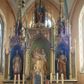 Zdjęcie nr 1: Ołtarz przyścienny, architektoniczny, trójosiowy, jednokondygnacyjny ze zwieńczeniem. Mensa skrzyniowa, prostopadłościenna. Na niej dwukondygnacyjne tabernakulum. W dolnej partii dekorowane postacia Baranka Apokaliptycznego drzwiczki ujęte otrołukowymi niszami wypełnionymi pękami kłosó. W drugiej kondygnacji tron wystawienia z niszą zdobioną rozetami i monogramem „IHS”, zwieńczoną nadwieszonymi łukami w ośli grzbiet z pinaklami i kwiatonami i ujętą parą klęczących aniołów. Predella wysoka, dekorowana fryzem arkadkowym, ostrołukowym, wypełnionym fragmentami wili winnej latorośli. W pierwszej kondygnacji retabulum trzy nisze prostokątne zamknięte od góry wimpergą na tle szczytu, ujete pinaklami wspartymi na służkach. Środkowa nisza wyższa i szersza od bocznych, rama dekorowana wyschniętą wicią roślinną, wszystkie zdobione ażurowym ornamentem ostrołukowym i żabkami; szczyty dekoruje fryz z rombami wypełnionymi czworoliśćmi.  Boczne nisze zwieńczone ustawionymi skośnie ażurowymi kapliczkami z pinaklami, zdobionymi żabkami i kwiatonami z rzeźbą mężczyzny z wiosłem po lewej i kobiety z lilią po prawej stronie. W środkowej niszy kondygnacji płaskorzeźbiona scena Nawiedzenia Najświętszej Marii Panny, w bocznych postać starego mężczyzny z kadzielnicą i św. Jan Chrzciciel. Kondygnacja ujęta uszakami utworzonymi z przypór z blendami i pinaklami. W zwieńczeniu ażurowa kapliczka powtarzająca kształt kapliczek wieńczących osie boczne pierwszej kondygnacji z niszą, w której figura św. Józefa z Dzieciątkiem. 
Struktura jasnozielona, nisze niebieskie, fragmenty dekoracji czerwone i niebieskie, detale złocone. 
