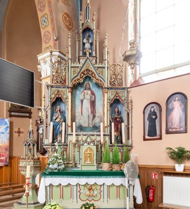 Zdjęcie nr 1: Ołtarz przyścienny, architektoniczny, trójosiowy, jednokondygnacyjny ze zwieńczeniem. Mensa skrzyniowa, prostopadłościenna, z antepedium dekorowanym płycinami.  W środkowej plakieta z symbolami płonącego serca oplecionego koroną cierniową, krzyża i kotwicy ujętymi kwitnącymi kwiatami i liśćmi. Na mensie tabernakulum w formie prostopadłościanu zwieńczonego wimpergą wypełnioną uskrzydlonymi główkami anielskimi, ujetą pinaklami. W centrum ostrołukowe drzwiczki z podobizną ukrzyżoanego Chrystusa. Predella trójdzielna ze środkową częścią wyższą, dekorowana fryzem z przenikających się arkadek, w środkowej części flankowanym blendami. W pierwszej kondygnacji retabulum trzy nisze prostokątne, z których środkowa zamknięta trójlistnie a boczne trójkątnie. Środkowa nisza wyższa i szersza od bocznych, rama dekorowana ornamentem, wszystkie zdobione ażurowym ornamentem roślinnym i żabkami; szczyty z fragmentami ornamentyki geometryczno-roślinnej.  Boczne nisze zwieńczone pinaklami, między którymi przenikające się żebra zwieńczone kwiatonem i fragmentami wolut, wypełnione wicią roślinną. W środkowej niszy kondygnacji obraz z przedstawieniem najświętszego Serca Jezusa, w bocznych figury Najświętszego Serca Marii z lewej i św. Jana Ewangelisty z prawej strony. Kondygnacja ujęta uszami utworzonymi z przypór z pinaklami. W zwieńczeniu ażurowa kapliczka ujęta pinaklami, w której figura modlącego się księdza. 
Struktura jasnozielona, nisze niebieskie, fragmenty dekoracji czerwone i niebieskie, detale złocone. 
