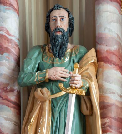 Zdjęcie nr 1: Rzeźba pełna, ustawiona na prostopadłościennym cokole. Figura ukazana w całej postaci, zwrócona frontalnie, w delikatnym kontrapoście, z lewym kolanem zgiętym. Głowa ustawiona na wprost, twarz podłużna, szczupła, okolona gęstym zarostem; wzrok zwrócony przed siebie. Ciemne włosy formują lok nad czołem i opadają na kark zasłaniając uszy, wąsy są szerokie, broda dzieli się w dwa pukle. Święty prawą, zgiętą rękę przyciska do piersi, w wyciągniętej przed siebie lewej trzyma rękojeść opartego o ziemię miecza. Apostoł jest ubrany zieloną w suknię sięgającą ziemi, wykończoną przy krawędziach złotym ornamentem geometrycznym; tkanina łamie się w sztywne, drobne fałdki. Beżowy, dekorowany złotym ornamentem roślinnym płaszcz otacza lewą rękę i jest zatknięty za pasem przy prawym biodrze. Polichromia naturalistyczna w odsłoniętych partiach ciała, miecz złocony i srebrzony. 