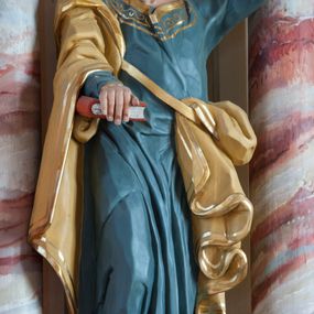 Zdjęcie nr 1: Rzeźba pełna, ustawiona na prostopadłościennym cokole. Figura ukazana w całej postaci, zwrócona frontalnie, w kontrapoście, z prawą nogą zgiętą. Głowa przechylona na lewe ramię, uniesiona; twarz prostokątna, okolona zarostem; wzrok uniesiony. Siwiejące włosy formują lok nad czołem, wąsy dzielą się na równoległe pasemka, broda skręcona w niewielkie loki. Święty prawą ręką dociska do ciała zamkniętą księgę, w lewej, uniesionej trzyma dwa klucze. Apostoł jest ubrany w niebieską suknię sięgającą ziemi, wykończoną przy krawędziach złotym ornamentem; beżowy, lamowany złotem płaszcz otacza prawą rękę i jest zatknięty za pasem przy lewym biodrze, opada ku ziemi dekoracyjnymi fałdami. Polichromia naturalistyczna w odsłoniętych partiach ciała, księga czerwona, o białych kartach, jeden klucz złocony, drugi srebrzony. 